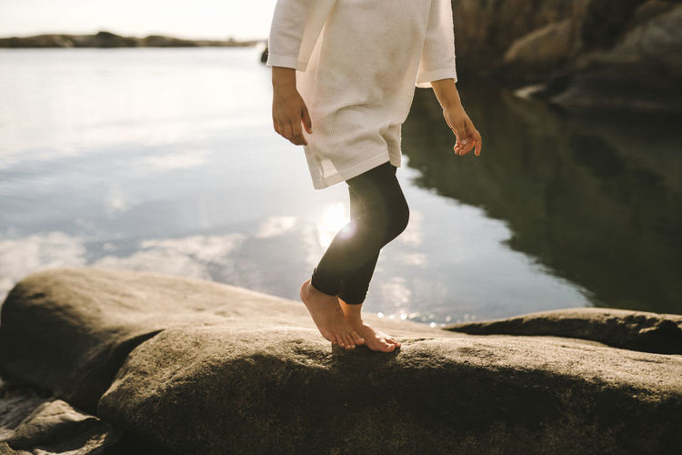 Girl walking on rocks at sea barefoot