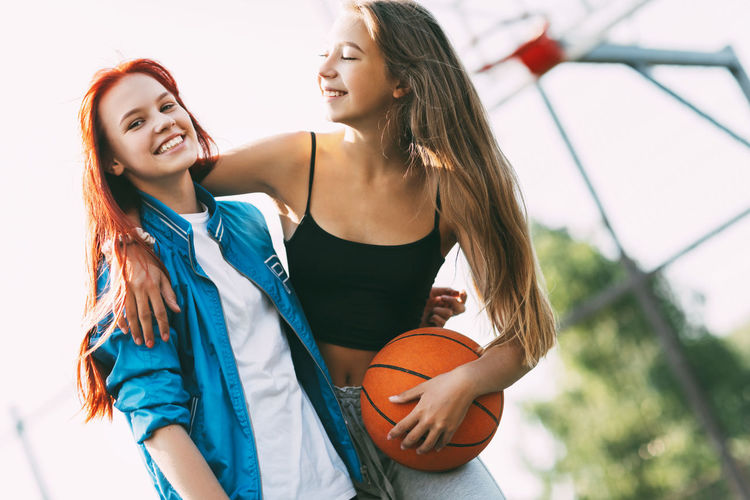 Two funny girls with a basketball hug each other after a game or workout. the concept of sports 