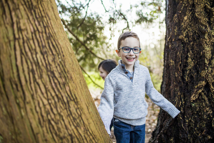 Young boy wearing glasses playing in the forest.