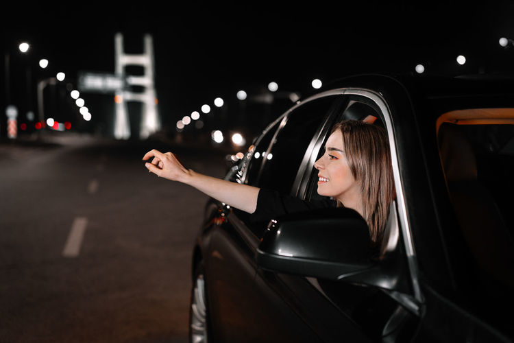 Portrait of beautiful young woman in car at night