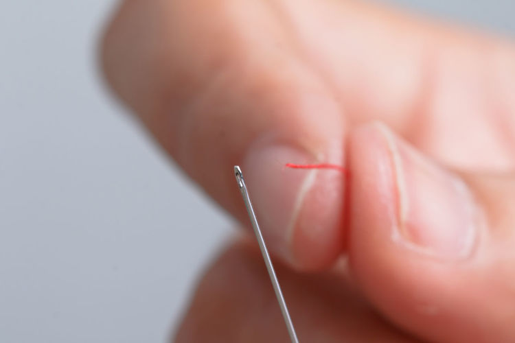 Cropped hands threading sewing needle 