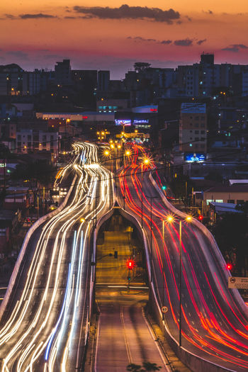 Light trails on bridge in city at dusk