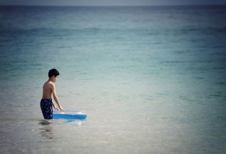 Shirtless boy with inflatable ring in sea