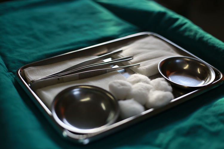 High angle view of cotton balls and equipment with bowls in tray on table in hospital