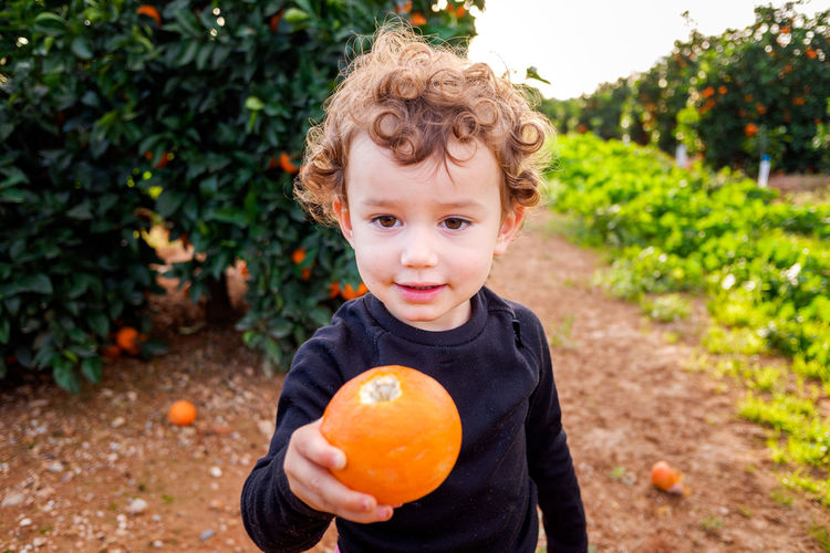 Cute girl holding orange outdoors