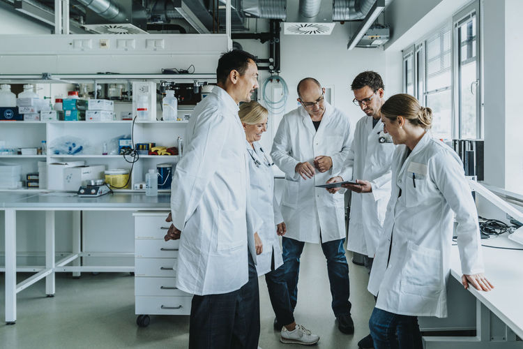 Team of scientist with digital tablet working together while standing at laboratory