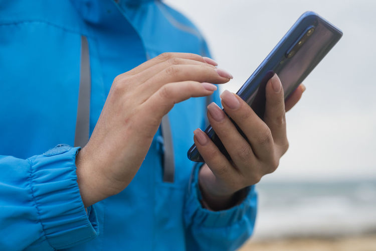 Midsection of man using mobile phone at beach