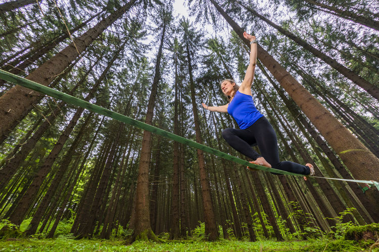 Young woman balancing on slackline in forest
