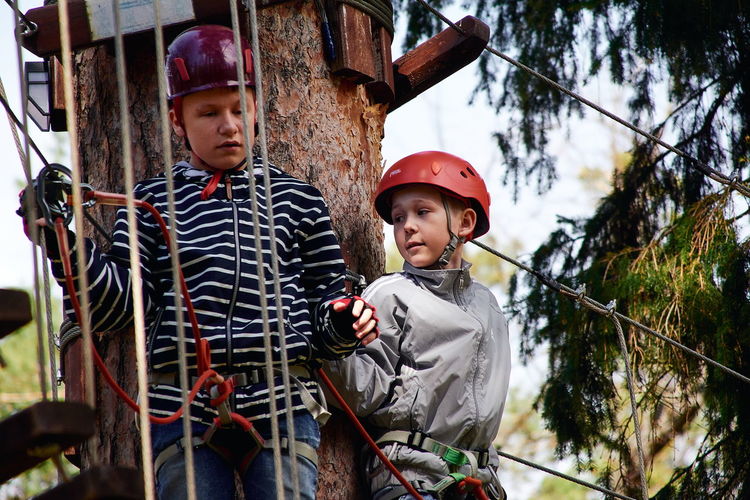 A childs in a helmet climbs a rope ladder.