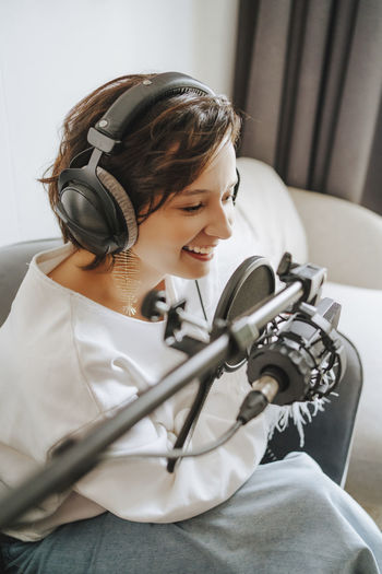 Happy musician recording podcast through microphone in studio