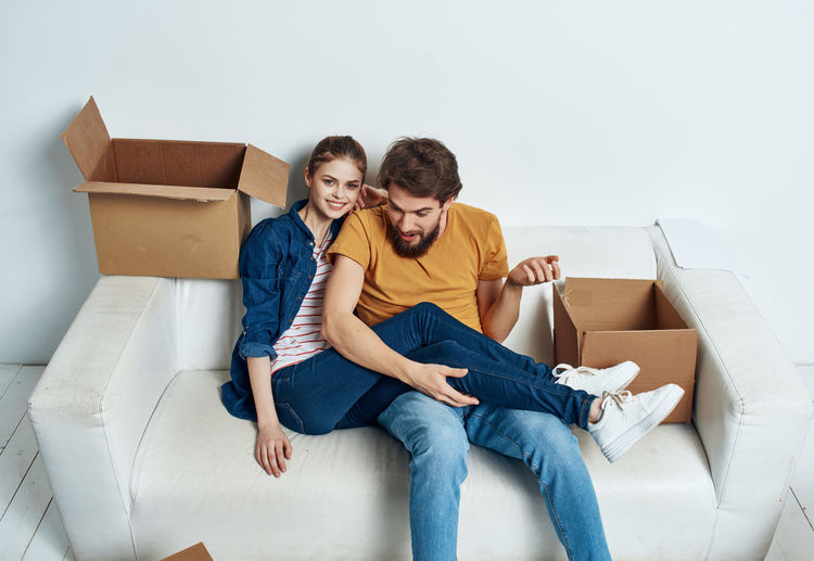 High angle view of couple sitting on sofa with cardboard boxes