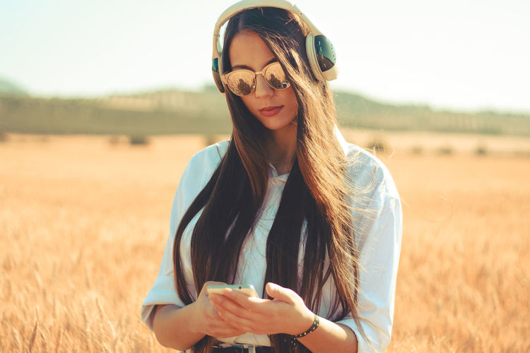 Woman listening music while using mobile phone on agricultural field