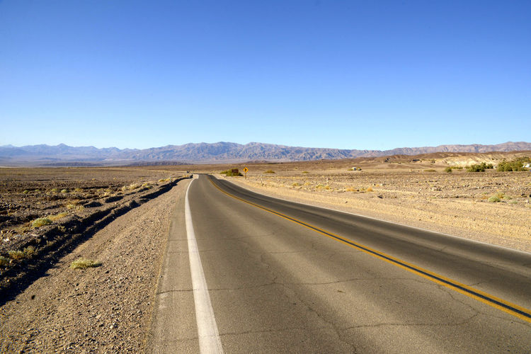 Empty road along landscape against clear sky