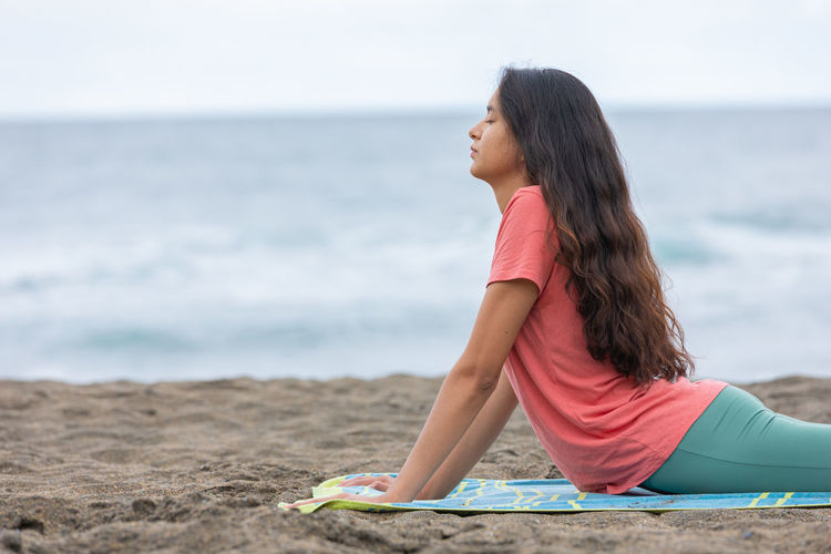 Side view of woman sitting at beach