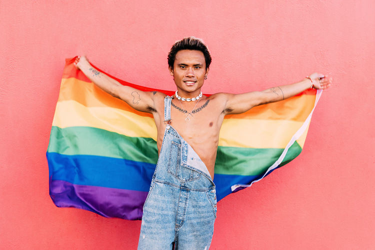 Portrait of young man holding rainbow flag