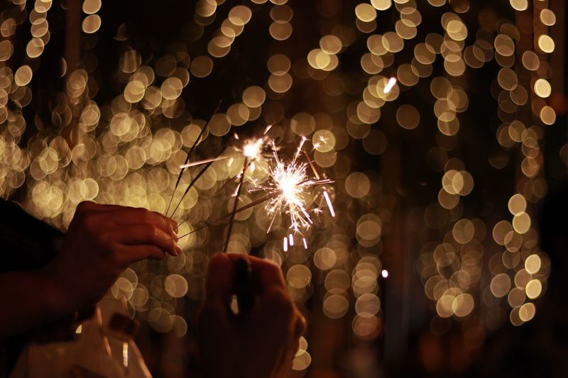 Close-up of hands holding sparklers at night