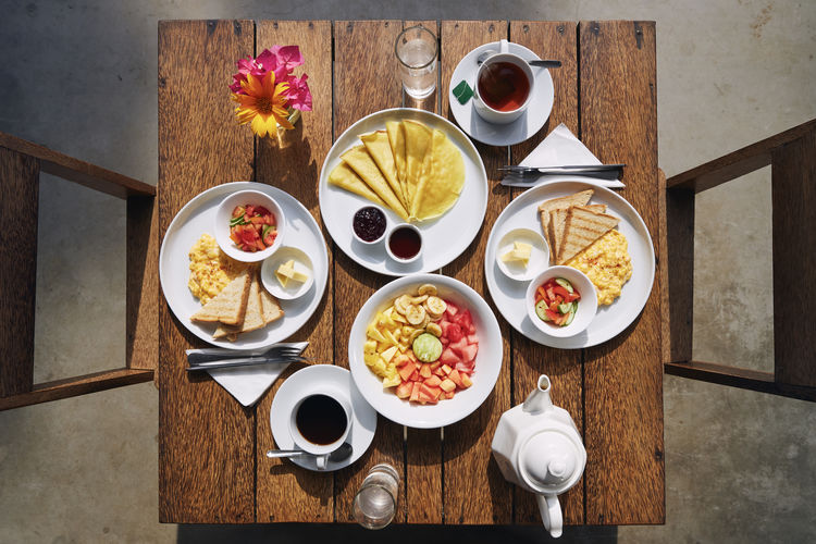 Hotel breakfast for two. table top view with scrambled eggs, pancakes and fruit salad.