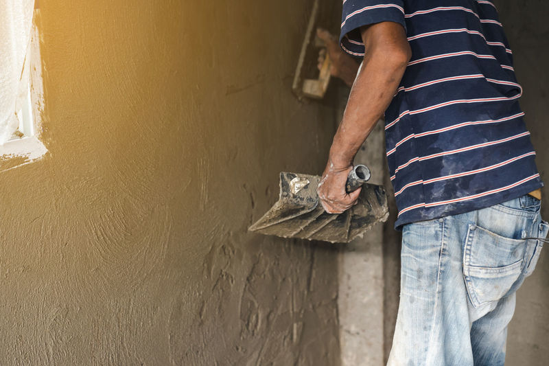 Worker man's hand plastering a wall with trowel