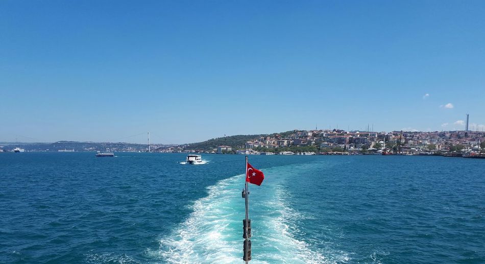 Turkish flag over sea against blue sky
