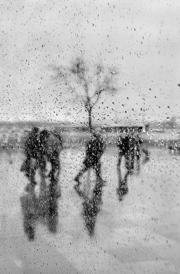 People on wet glass against sea