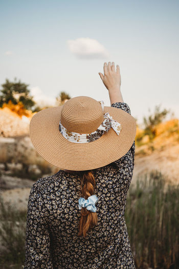 Woman with hat touching the clouds