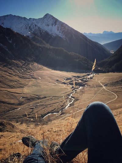 Low section of man standing on mountain against sky