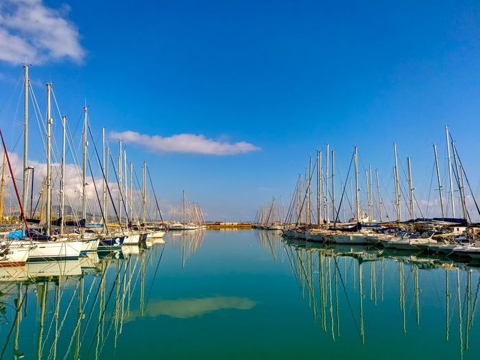Sailboats in harbor against blue sky
