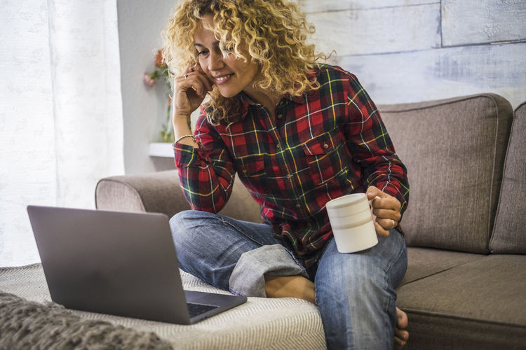 Smiling woman using laptop sitting at home