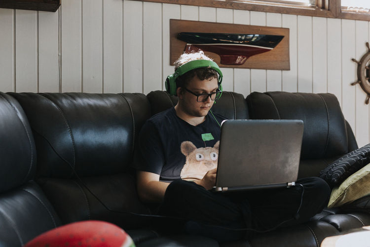 Teenage boy on sofa using laptop