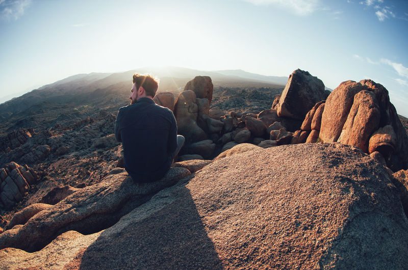 Rear view of man sitting on rock