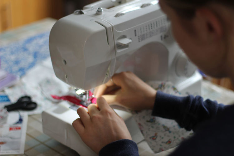 Cropped image of woman stitching fabric in sewing machine