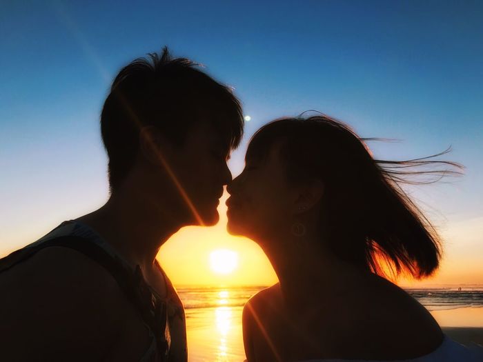 Silhouette of couple kissing against sky during sunset