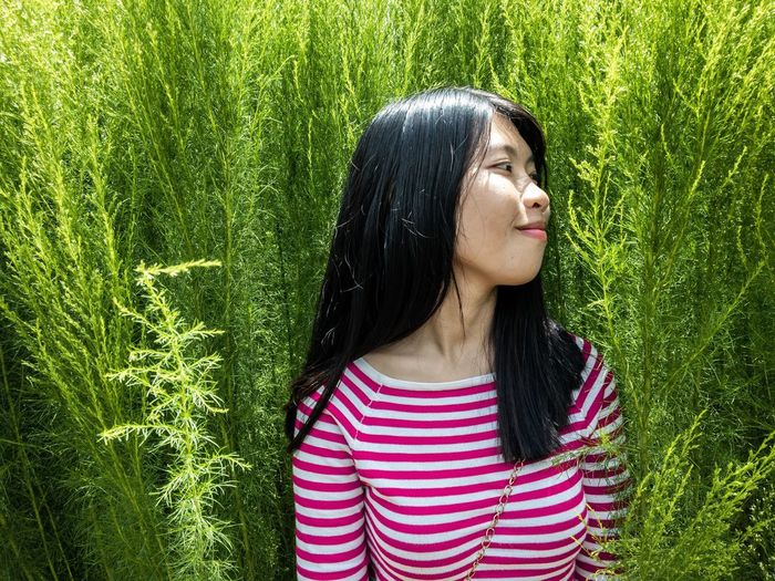 Portrait of young woman standing in green grass