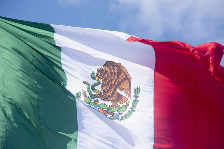 Close-up of mexican flag emblem against the blue sky