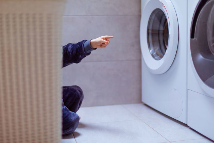 Boy pointing at washing machine at home