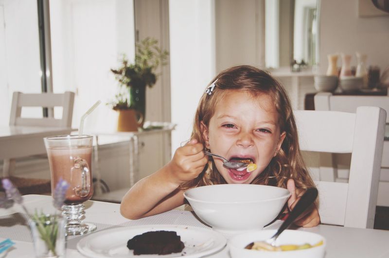 Close-up of girl eating food at home
