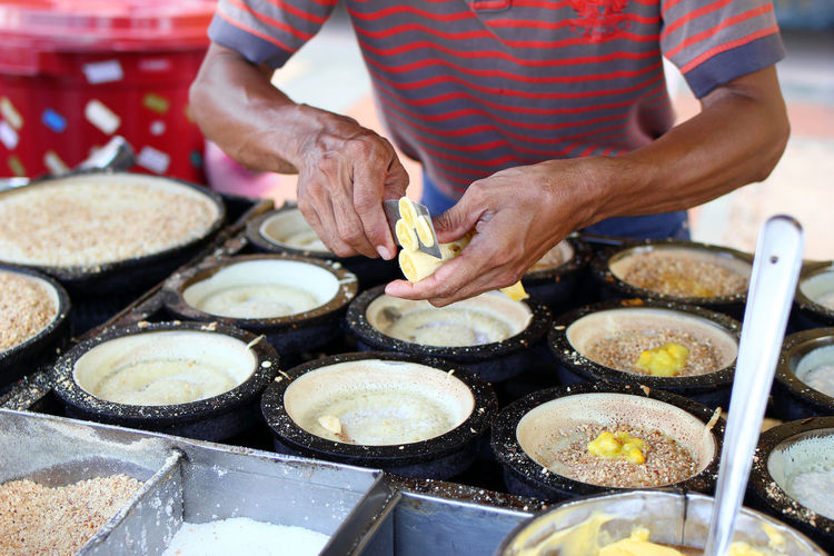 Unrecognizable man is cooking traditional malaysian street food apam balik - thick soft pancake.