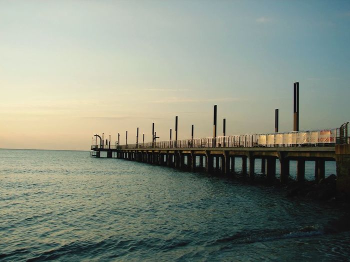Pier on sea against sky during sunset