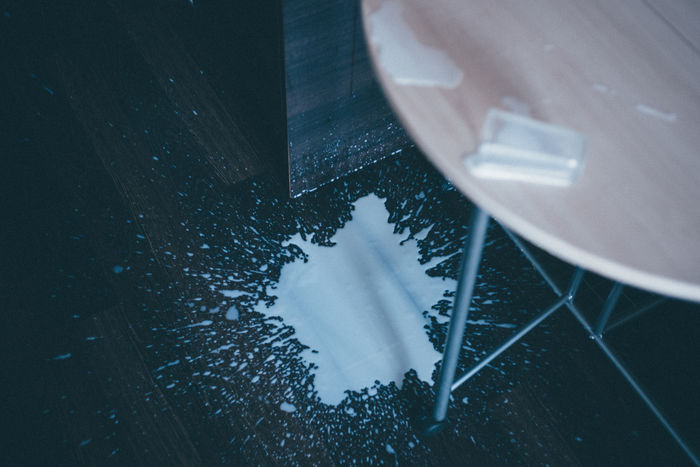 High angle view of milk spilling from glass on floor