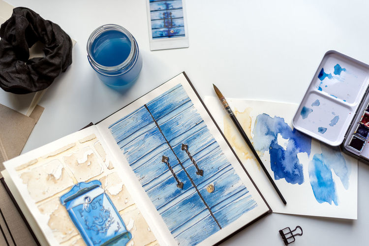 An open watercolor sketchbook lies on a white table.