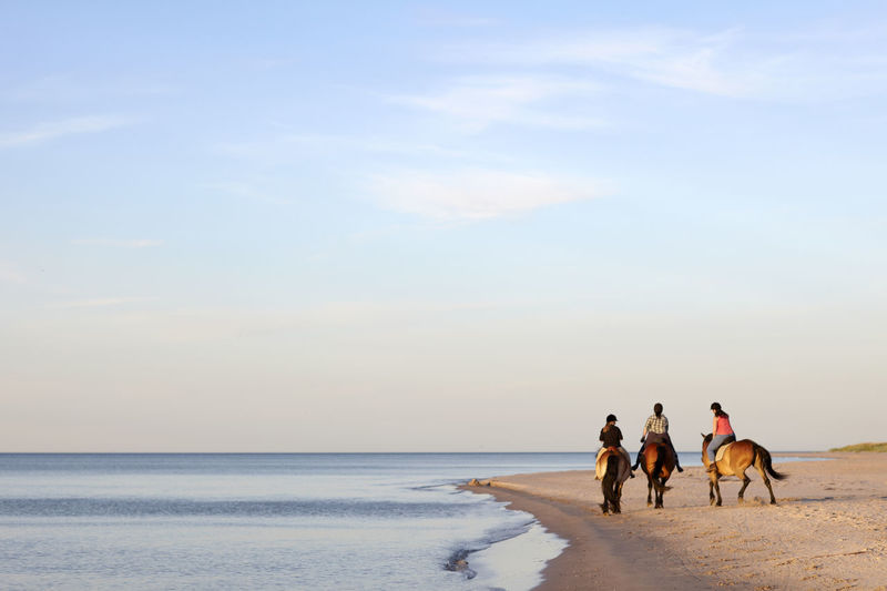 Three women horseback riding on beach