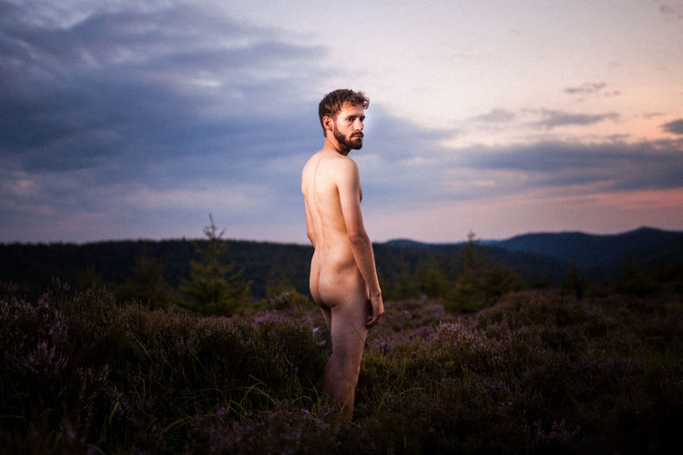 Naked young man standing on field