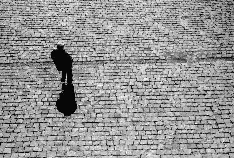 Rear view of man walking against brick wall