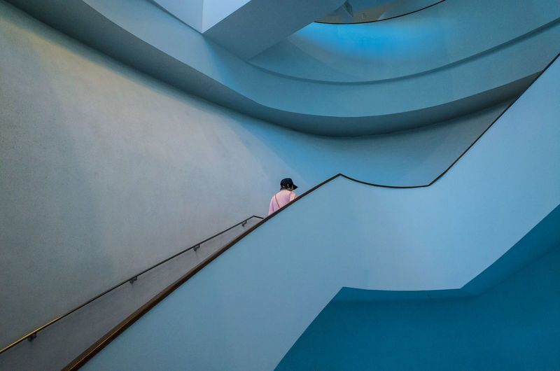 Architecture Blue Building Building Exterior Built Structure Day Effort Full Length Leisure Activity Lifestyles Low Angle View Nature One Person Outdoors Railing Real People Side View Staircase Steps And Staircases Wall - Building Feature