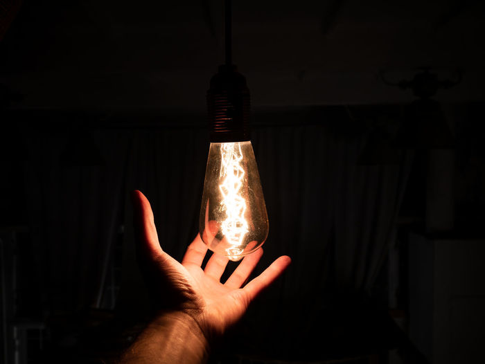 Midsection of person holding light bulb