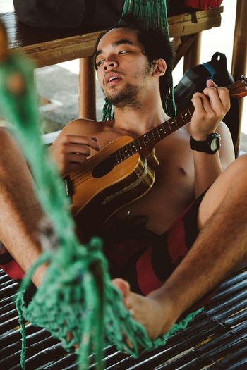 Shirtless man playing guitar