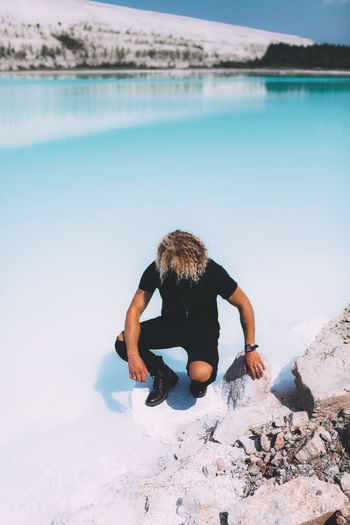 High angle view of man sitting on frozen lake