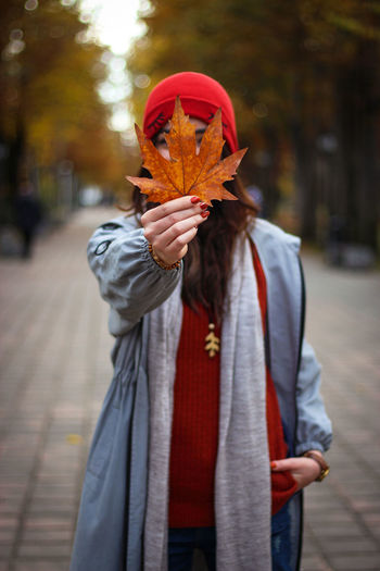 Midsection of person with umbrella standing on street during autumn