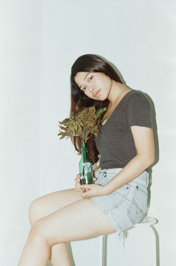 Portrait of teenage girl sitting against wall