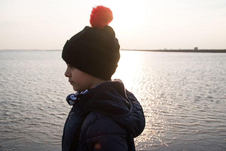 Lovely boy wearing winter clothes next to the sea